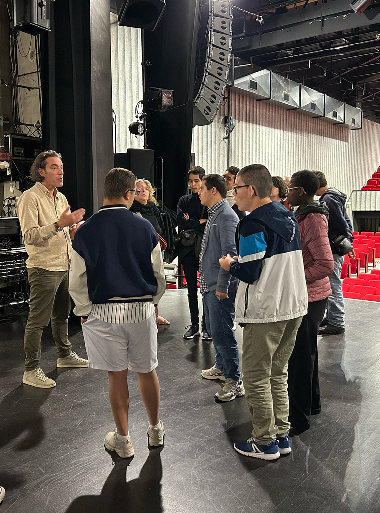 photo de 10 personnes sur une scène dans une salle de spectacle, un homme parle